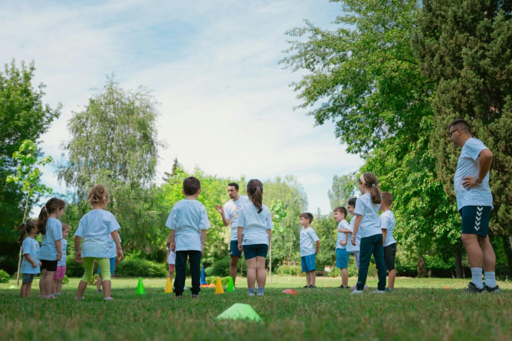 Group of kids learning and playing with teachers in a sunny park.
