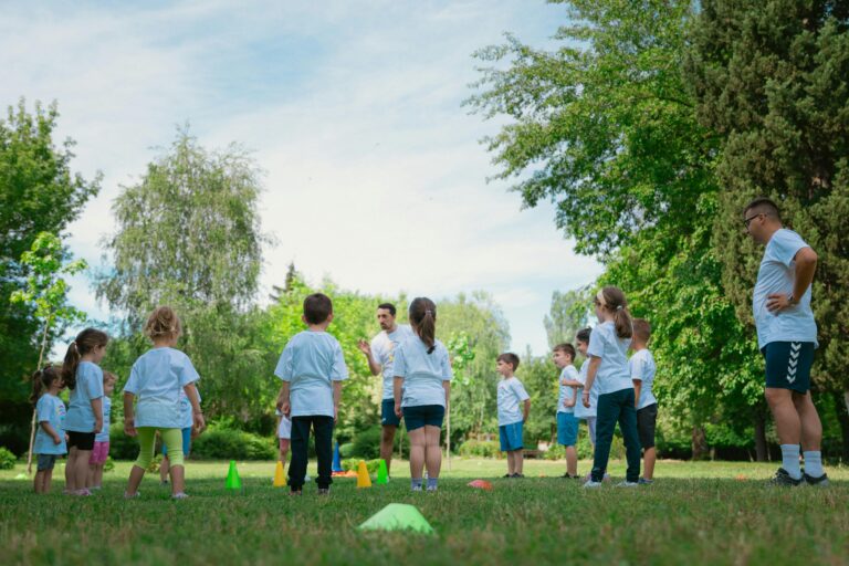 Group of kids learning and playing with teachers in a sunny park.