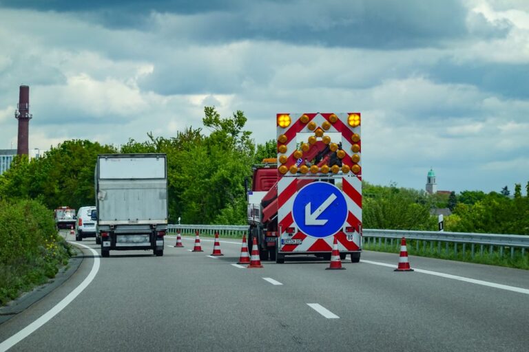 City highway under maintenance with traffic cones and warning signs directing vehicles.